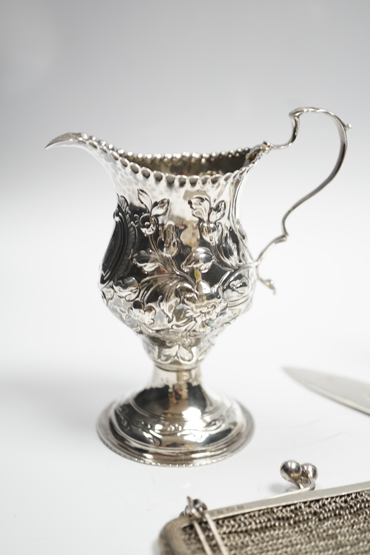 A George III silver inverted pear shaped cream jug, with later embossed decoration, London, 1774, a pair of late Victorian bottle shaped pepperettes and other small silver.